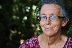 Photo by Anthony Metcalfe on Unsplash of middle-aged woman with glasses, smiling.